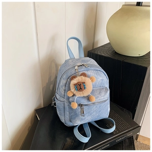 Detail van lichtblauwe denim mini-rugzak met een kaki pluche dierenhanger als decoratie
