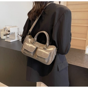 Deep grey glossy leather handbag shown on model with shoulder strap and retro hardware