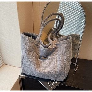 Detail of grey plush tote bag featuring soft fleece texture and leather buckle detail