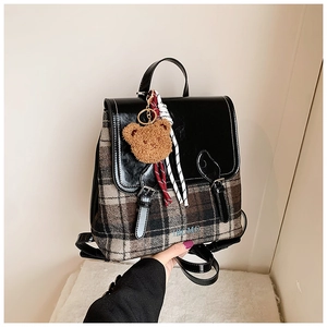 Dettaglio zaino vintage a quadri con ciondolo a orsetto e logo TBOME sulla borsa