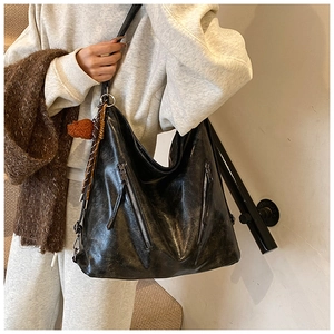 Close-up of black leather tote bag with silver zippers and a cute brown bear charm