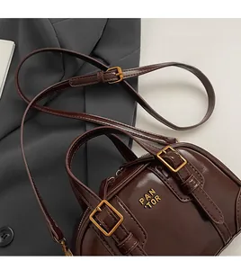 Close-up of dark brown glossy leather handbag featuring golden logo and metal buckles