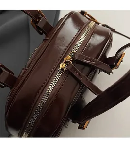 Detailed close-up of smooth metal double zippers on a dark brown vintage leather bag