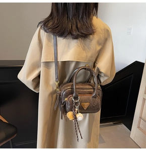 Détail du sac Boston en cuir marron vintage avec triangle doré et accessoire de baseball