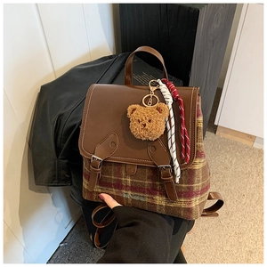 Dettaglio dello zaino vintage scozzese con patta in pelle e ciondolo a forma di orso