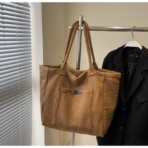 Detail of a brown plush tote bag with fuzzy texture hanging on a metal rack