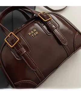 Close-up of vintage dark brown glossy leather handbag with gold buckles and text details