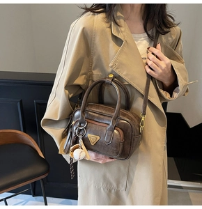 Détail du mini sac Boston marron foncé vintage avec breloque baseball et logo métal