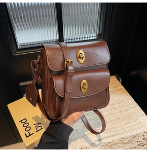 Close-up of vintage brown leather crossbody bag featuring dual metal twist-lock buckles