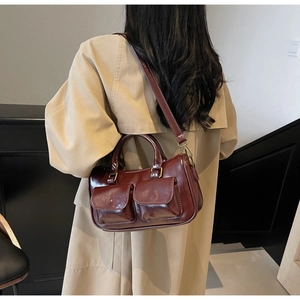 Detail of vintage burgundy glossy leather handbag with front pockets and bronze hardware