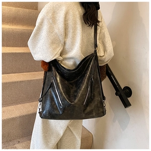 Detail of vintage black oil wax leather tote bag with silver zippers on stairs