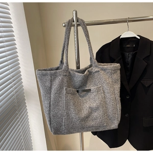 Detail of grey fuzzy fleece tote bag showing thick wool-blend texture and front pocket