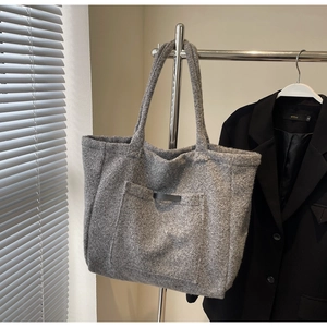 Detailed close-up of grey plush tote bag with front pocket hung on a metal rack