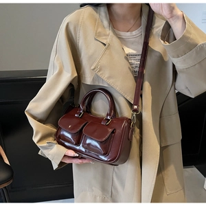 Detail of vintage burgundy leather handbag with front flap pockets and gold hardware