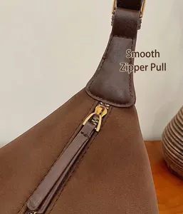 Détail montrant la fermeture éclair dorée et le cuir marron mat du sac à main
