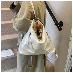 Detail of metallic pearl hobo bag with silver zippers and woven charm accessory