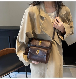 Close-up of retro dark brown leather crossbody bag with dual compartments and gold twists