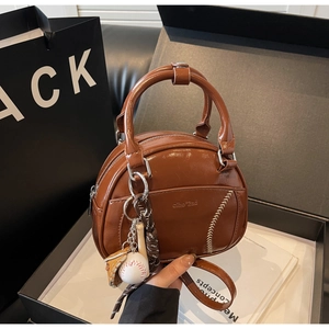 Detailansicht der braunen Vintage-Tasche mit Baseball-Anhängern in einer edlen Geschenkbox