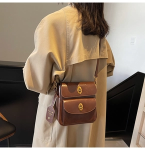 Detail of brown vintage crossbody bag with gold twist locks and branded leather tag
