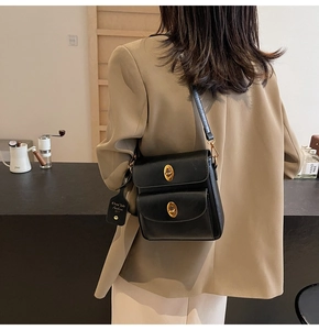 Detail of black crossbody bag with double gold turn-lock clasps and branded leather tag