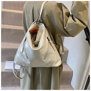 Detail of soft pearl white leather backpack with metal zippers and plush charm on model