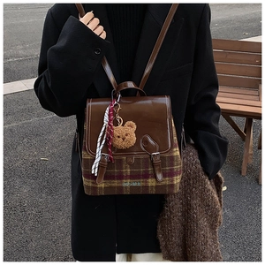 Dettaglio dello zaino in lana a quadri stile British con patta in pelle e ciondolo orso