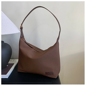 Détail du sac croissant en cuir marron foncé avec fermeture éclair et logo gaufré