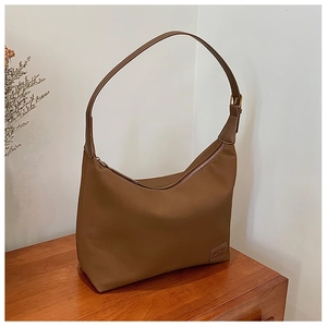 Gros plan détaillé du sac à bandoulière marron minimaliste sur bois avec fleurs séchées
