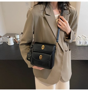 Detail of a black leather crossbody bag with double gold oval twist locks and fine strap