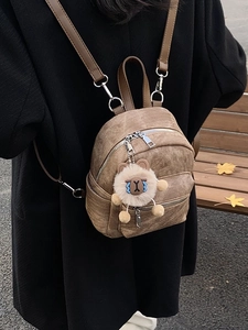 Retro bruine mini rugzak met pluchen hanger op een parkbankje in de herfst