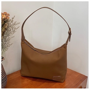 Vue détaillée du sac hobo marron en nylon avec logo BEIKAMU en cuir sur table en bois