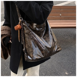 Outdoor shot of a vintage brown tote bag with metal zippers and a plush charm