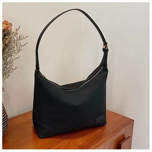 Détail du sac hobo en nylon noir avec fermeture éclair et étiquette tissée de marque