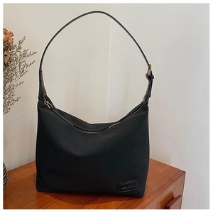Détail d'un sac hobo en nylon noir avec logo en cuir et fermeture éclair métallique