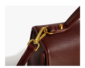 Close-up of premium dark burgundy lychee leather with matte gold swivel hook hardware