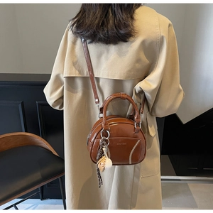 Detail der braunen Vintage Leder-Bowlingtasche mit Baseballnähten und Anhängern