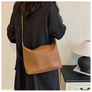 Détail du sac hobo marron avec fermeture éclair et écusson logo en cuir gaufré