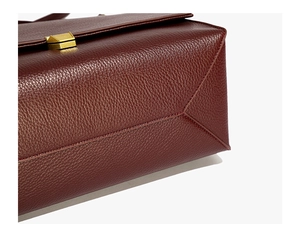 Detailed close-up of dark burgundy pebbled leather and matte gold metal lock hardware