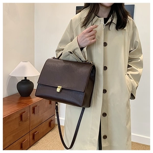 Brown lychee leather crossbody bag styled in a minimalist interior setting with soft lighting