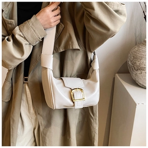 Dettaglio della borsa a tracolla in pelle beige con grande fibbia dorata decorativa