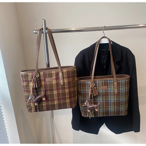Detail of plaid tote bags featuring leather dachshund charms and stylish tassels