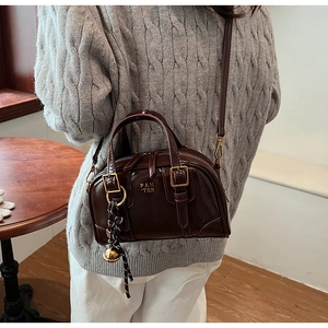Detail of vintage coffee brown bowling bag with gold hardware and woven charm