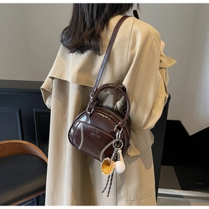 Streetstyle-Aufnahme einer dunkelbraunen Lacklederhandtasche mit Baseball-Nähten