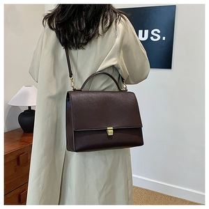 Detail view of dark brown pebbled leather crossbody bag with gold lock hardware
