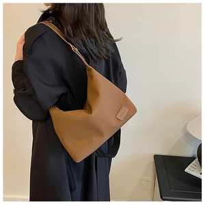 Gros plan du sac cabas marron en cuir minimaliste montrant la texture et l'étiquette
