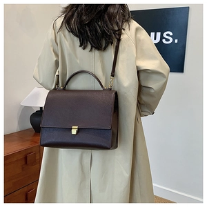 Detail of vintage coffee crossbody bag textured leather on model wearing beige trench coat