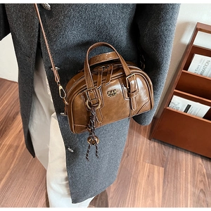 Close-up of a vintage brown leather Boston bag with gold hardware and dual zippers