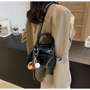 Detail einer schwarzen Lackleder-Bowlingtasche mit Baseballnähten und Handschuhanhänger