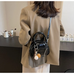 Schwarze Lackleder-Bowlingtasche im Retro-Look mit Baseball-Nähten getragen von Model