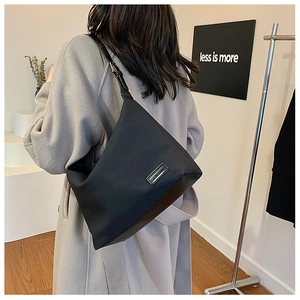 Gros plan sur un grand sac cabas noir en nylon avec bandoulière en cuir et logo chic
